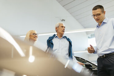 Senior couple couple talking with salesperson in car dealership - ZEDF00739