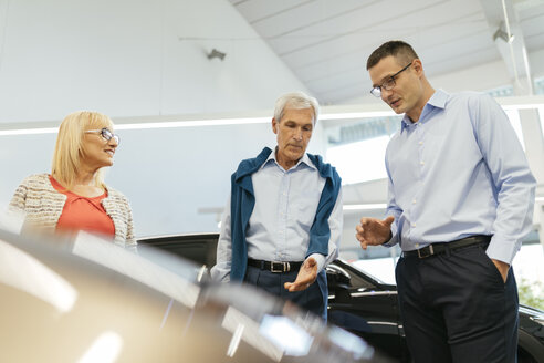 Älteres Ehepaar im Gespräch mit einem Verkäufer in einem Autohaus - ZEDF00740