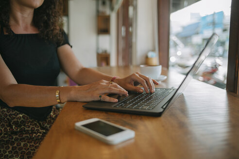 Frau benutzt Laptop in einem Café - MOMF00175