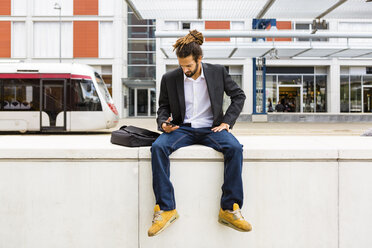 Young businessman with dreadlocks using smartphone while waiting at station - MGIF00021
