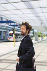 Porträt eines jungen Geschäftsmannes mit Dreadlocks, der am Bahnhof wartet - MGIF00026