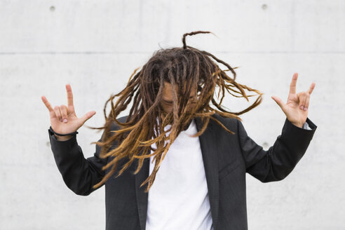 Young businessman tossing his dreadlocks showing Rock And Roll Sign - MGIF00031