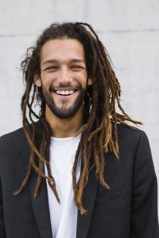 Porträt eines lächelnden jungen Geschäftsmannes mit Dreadlocks, lizenzfreies Stockfoto