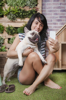 Frau und französische Bulldogge machen ein Selfie auf der Terrasse - RTBF00925