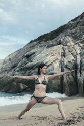 Greece, Chalkidiki, young woman practicing yoga on the beach - BZF00368