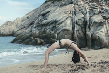 Griechenland, Chalkidiki, junge Frau übt Yoga am Strand - BZF00369