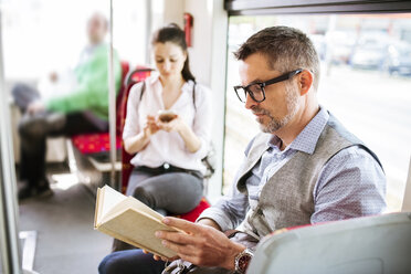 Geschäftsmann in Straßenbahn liest Buch - HAPF01767