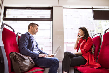 Businessman and woman with laptop and smartphone in bus - HAPF01776