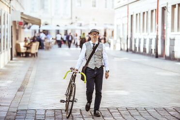 Älterer Geschäftsmann schiebt Fahrrad in der Stadt - HAPF01781