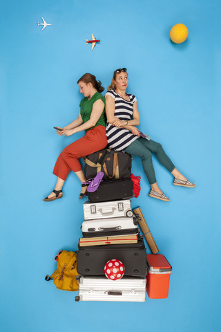 Freunde sitzen auf einem Stapel Gepäck und warten auf den Abflug, schauen gelangweilt, lizenzfreies Stockfoto