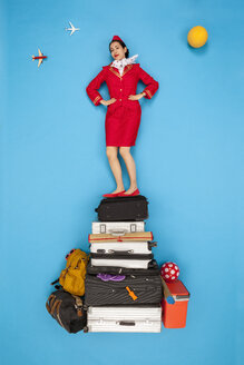 Selbstbewusste Flugbegleiterin auf einem Haufen Gepäck stehend - BAEF01371