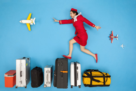 Flugbegleiterin springt über eine Reihe von Gepäckstücken, lizenzfreies Stockfoto
