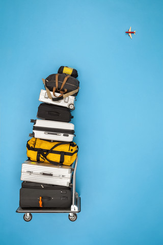 Gestapeltes Gepäck und ein in den Himmel fliegendes Flugzeug, lizenzfreies Stockfoto