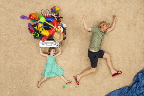 Vater und Tochter laufen zum Meer und tragen Strandausrüstung auf dem Kopf, lizenzfreies Stockfoto