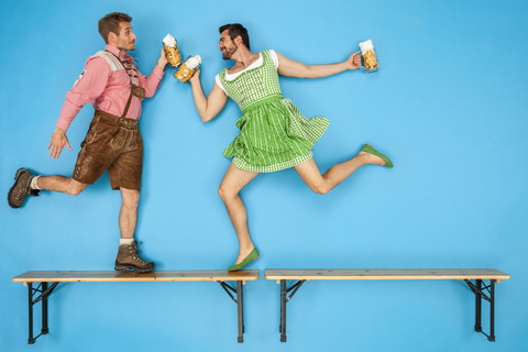 Schwules Paar auf dem Oktoberfest tanzt auf Bierbänken, lizenzfreies Stockfoto