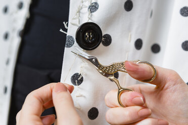 Woman's hands stitching button on a dress, close-up - MGIF00041