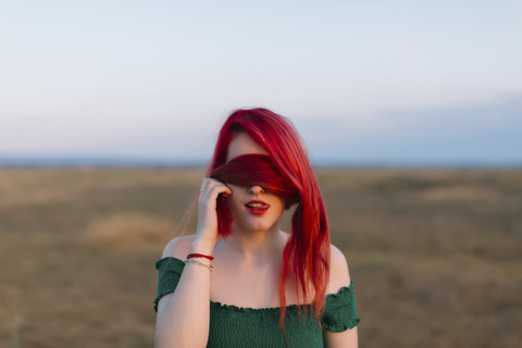 Redheaded woman covering eyes with her hair stock photo