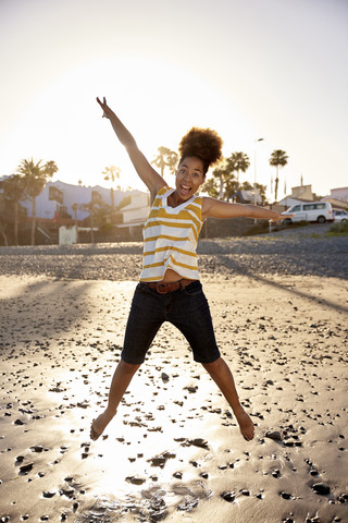 Happy woman jumping in the air on the beach stock photo