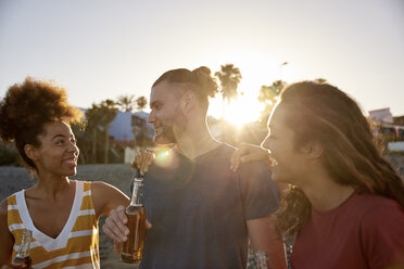 Drei Freunde mit Bierflaschen am Strand bei Sonnenuntergang - PACF00033