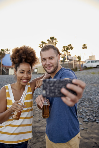 Zwei Freunde mit Bierflaschen machen ein Selfie am Strand, lizenzfreies Stockfoto