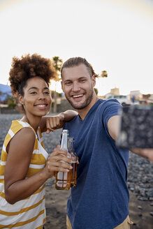 Zwei Freunde mit Bierflaschen machen ein Selfie am Strand - PACF00046