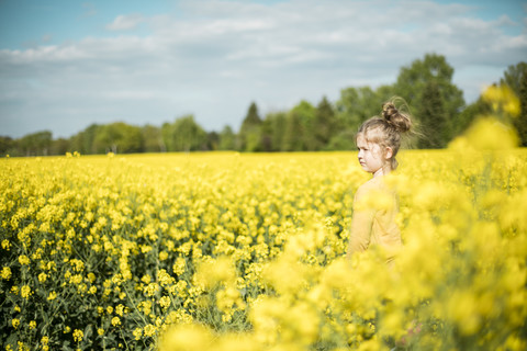 Mädchen im Rapsfeld stehend, lizenzfreies Stockfoto