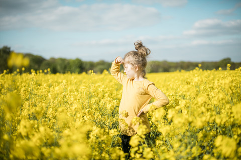 Girl standing in rape field looking out stock photo