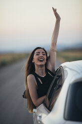 Happy woman leaning out of car window - JPF00246