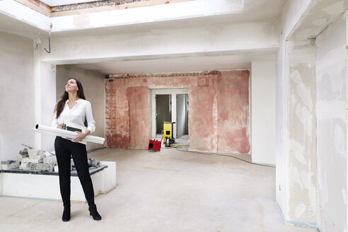 Woman in empty apartment looking around - DMOF00031