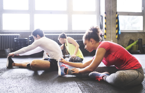 Three young people stretching in gym stock photo