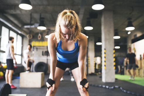 Erschöpfte junge Frau im Fitnessstudio, die eine Pause macht - HAPF01805