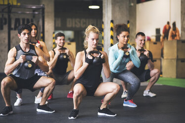 Eine Gruppe junger fitter Menschen hebt Kettlebells im Fitnessstudio - HAPF01831