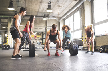 Group of young fit people cheering at man weightlifting in gym - HAPF01838