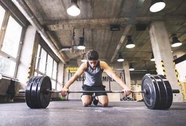 Junger Sportler beim Training mit einer Langhantel im Fitnessstudio - HAPF01849