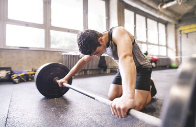 Junger Sportler beim Training mit einer Langhantel im Fitnessstudio - HAPF01850