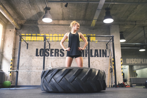 Junge Frau, die mit einem Traktorreifen im Fitnessstudio trainiert, lizenzfreies Stockfoto