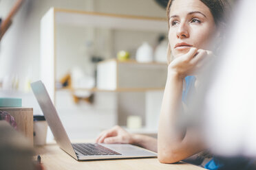 Young woman using laptop at desk at home - KNSF01635