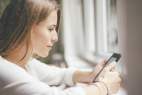 Young woman holding portable device at the window - KNSF01639