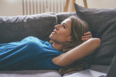 Relaxed young woman lying on couch at home - KNSF01646