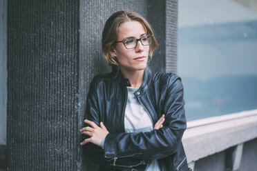 Young woman with glasses and leather jacket looking sideways - KNSF01649