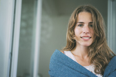 Porträt einer lächelnden jungen Frau, eingewickelt in eine Decke - KNSF01669