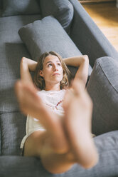 Young woman lying on couch at home - KNSF01682