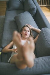 Young woman lying on couch at home - KNSF01685