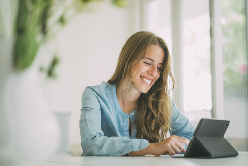 Smiling young woman using tablet at home - KNSF01694