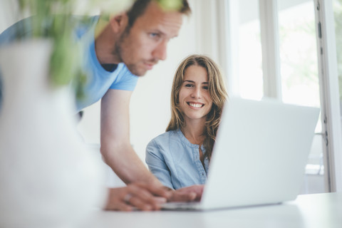Lächelnde junge Frau und Mann verwenden Laptop zu Hause, lizenzfreies Stockfoto