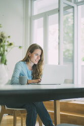 Young woman using laptop at home - KNSF01696