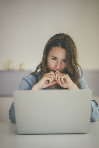 Junge Frau schaut auf Laptop, lizenzfreies Stockfoto