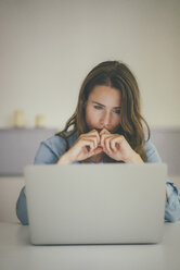 Junge Frau schaut auf Laptop - KNSF01699