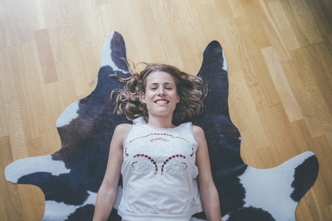 Portrait of smiling young woman lying on fur on the floor stock photo