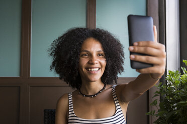 Glückliche junge Frau nimmt Selfie in einem Café - ABZF02145